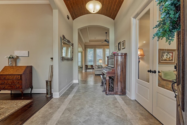 entryway with arched walkways, a ceiling fan, lofted ceiling, and baseboards