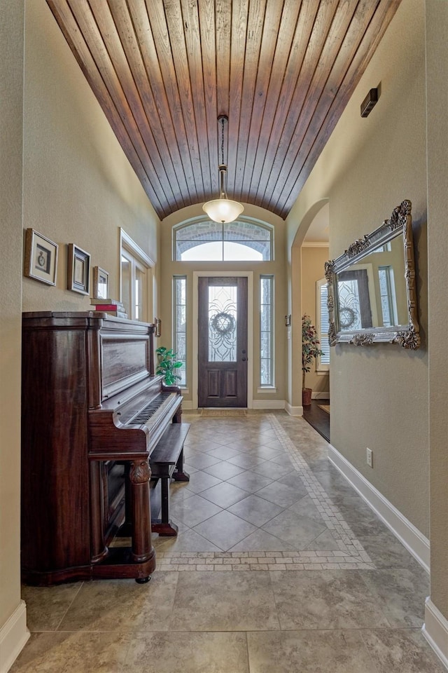 foyer entrance featuring arched walkways, wooden ceiling, baseboards, and vaulted ceiling