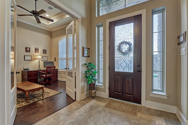 foyer entrance featuring visible vents, ornamental molding, dark wood finished floors, baseboards, and a raised ceiling