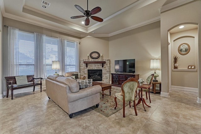 living area featuring a tray ceiling, visible vents, baseboards, and ornamental molding