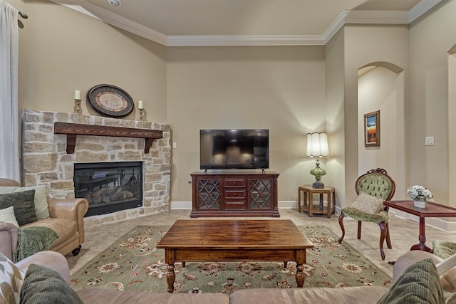 living room featuring baseboards, arched walkways, ornamental molding, and a fireplace