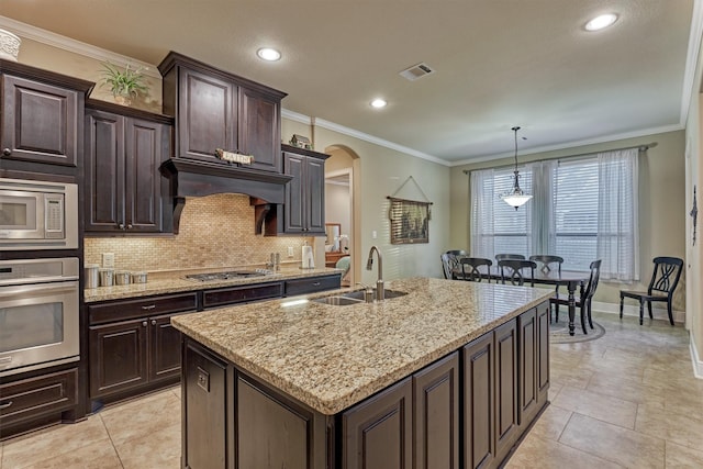 kitchen featuring visible vents, arched walkways, a sink, stainless steel appliances, and tasteful backsplash