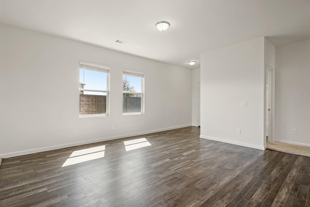 empty room with visible vents, baseboards, and dark wood-style flooring