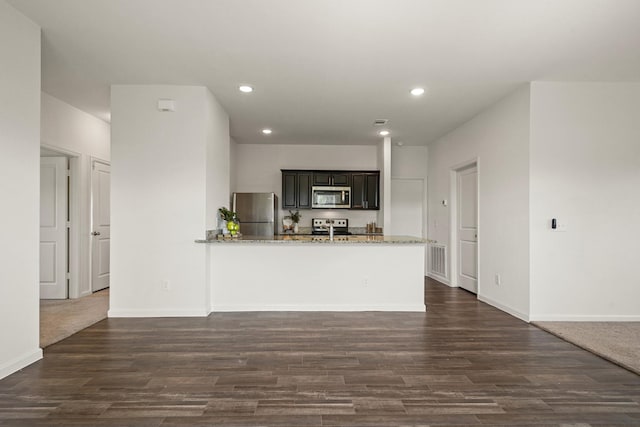 kitchen featuring recessed lighting, stainless steel appliances, dark wood-type flooring, and light stone countertops