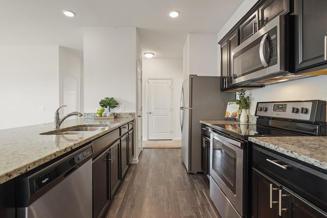 kitchen with a sink, dark wood-type flooring, light stone countertops, and stainless steel appliances