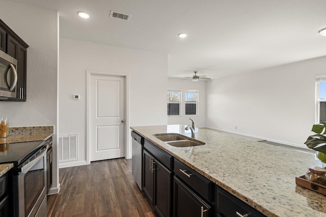 kitchen with a sink, light stone counters, dark wood-style floors, recessed lighting, and stainless steel appliances