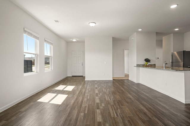 unfurnished living room featuring baseboards, visible vents, recessed lighting, dark wood-style flooring, and a sink