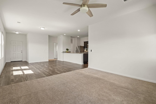 unfurnished living room with dark wood finished floors, recessed lighting, dark colored carpet, baseboards, and ceiling fan