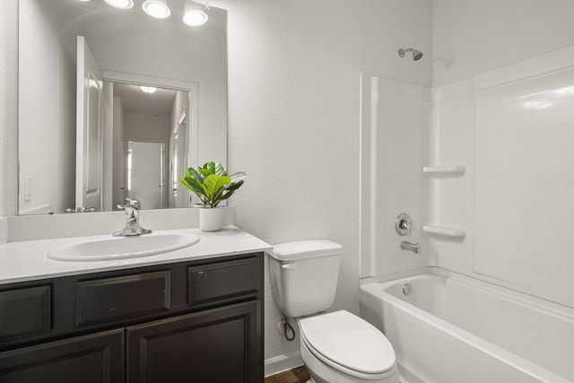 bathroom with vanity,  shower combination, toilet, and a textured wall