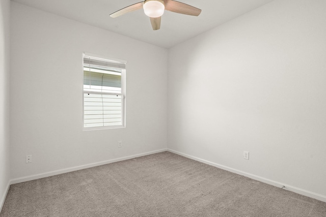 carpeted empty room featuring baseboards and a ceiling fan