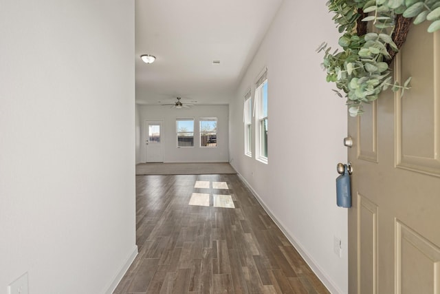 hallway featuring dark wood finished floors and baseboards