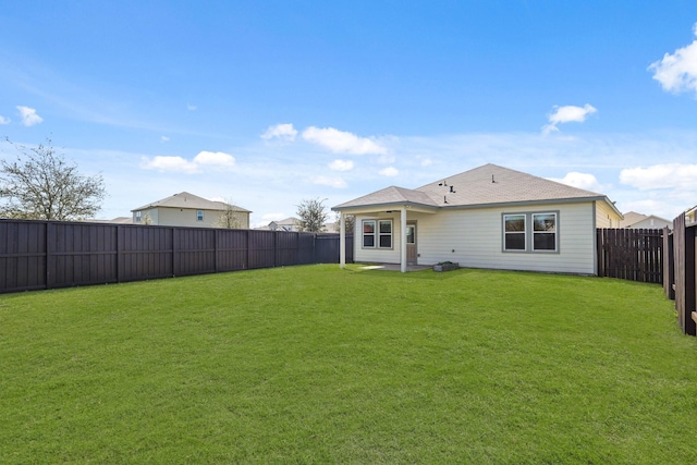 rear view of property featuring a lawn and a fenced backyard