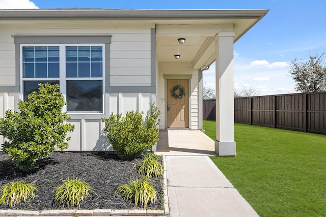 doorway to property featuring a yard and fence