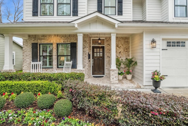 doorway to property with board and batten siding, a porch, brick siding, and a garage