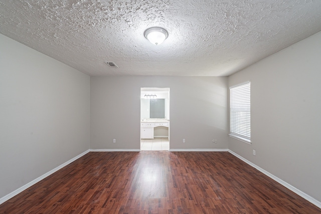 unfurnished room featuring visible vents, a textured ceiling, baseboards, and wood finished floors