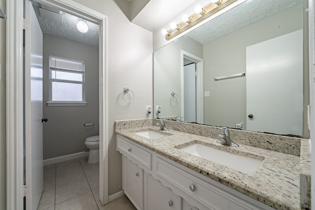 bathroom with tile patterned flooring, toilet, a textured ceiling, and a sink