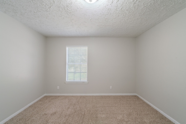 carpeted spare room featuring baseboards and a textured ceiling