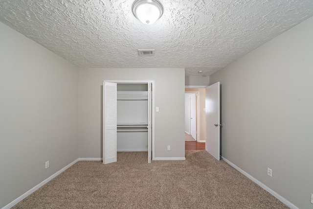 unfurnished bedroom with carpet, visible vents, baseboards, a closet, and a textured ceiling