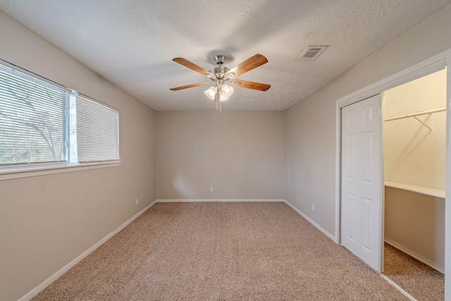 unfurnished bedroom featuring visible vents, ceiling fan, baseboards, light carpet, and a textured ceiling