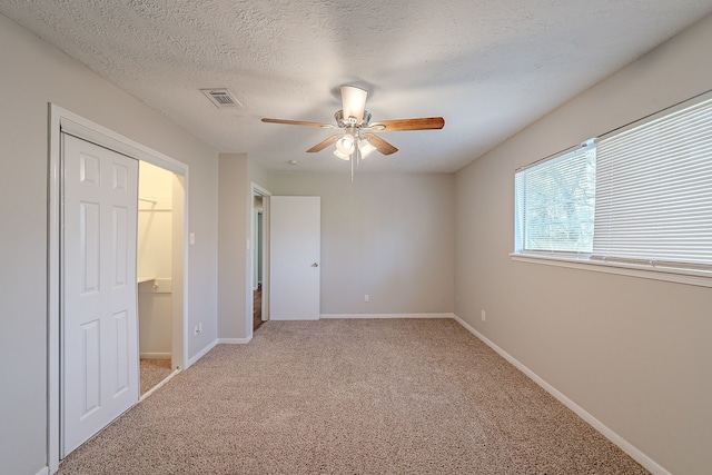 unfurnished bedroom featuring visible vents, light colored carpet, a textured ceiling, and baseboards