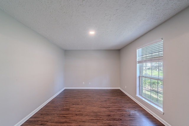 empty room featuring baseboards, dark wood-type flooring, and a textured ceiling