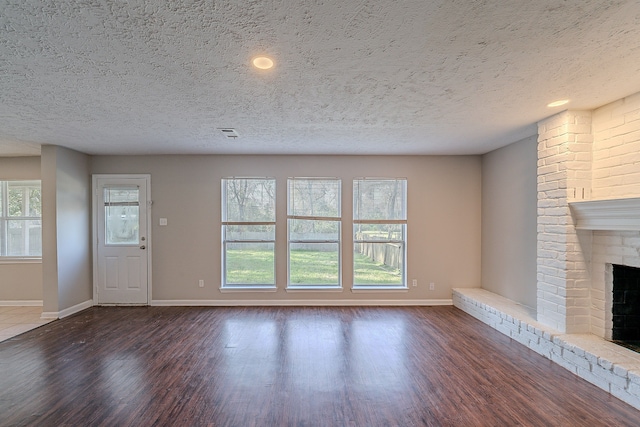 unfurnished living room featuring wood finished floors, a fireplace, visible vents, and baseboards