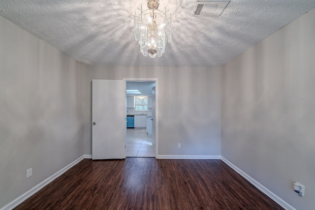 unfurnished room with visible vents, baseboards, an inviting chandelier, and wood finished floors