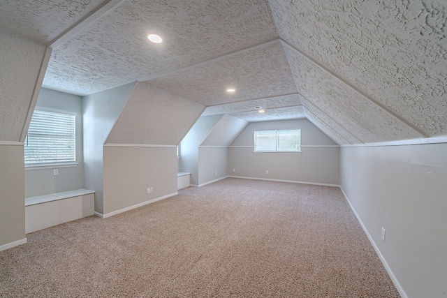 bonus room with baseboards, lofted ceiling, a textured ceiling, and carpet flooring