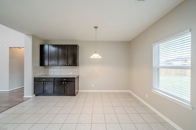 interior space with hanging light fixtures, light countertops, baseboards, and backsplash