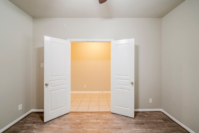 empty room featuring baseboards, a ceiling fan, and light wood finished floors