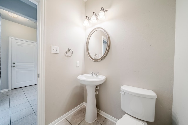 half bath with tile patterned flooring, toilet, and baseboards