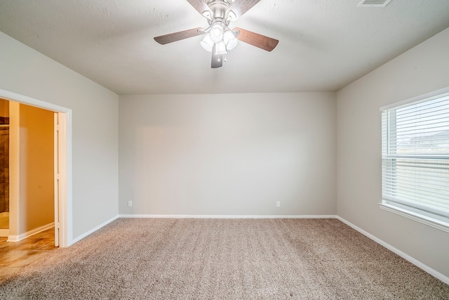 empty room featuring light carpet, a ceiling fan, and baseboards