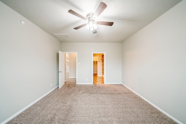 unfurnished bedroom featuring ceiling fan, baseboards, attic access, light carpet, and a textured ceiling