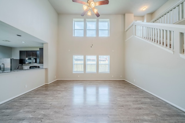 unfurnished living room with ceiling fan, plenty of natural light, and wood finished floors