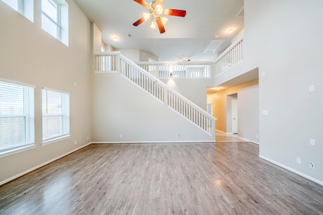 unfurnished living room with a healthy amount of sunlight, stairs, baseboards, and wood finished floors