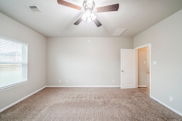 unfurnished room with baseboards, visible vents, ceiling fan, a textured ceiling, and light colored carpet