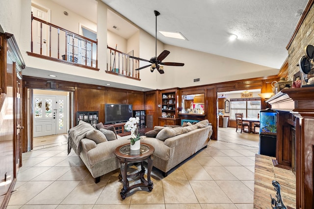 living area featuring visible vents, a textured ceiling, light tile patterned flooring, and a ceiling fan