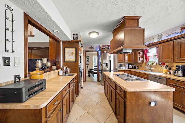 kitchen featuring a center island, light countertops, light tile patterned floors, stainless steel appliances, and a sink