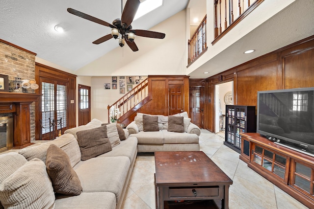 living room with a brick fireplace, stairway, light tile patterned floors, a towering ceiling, and a ceiling fan