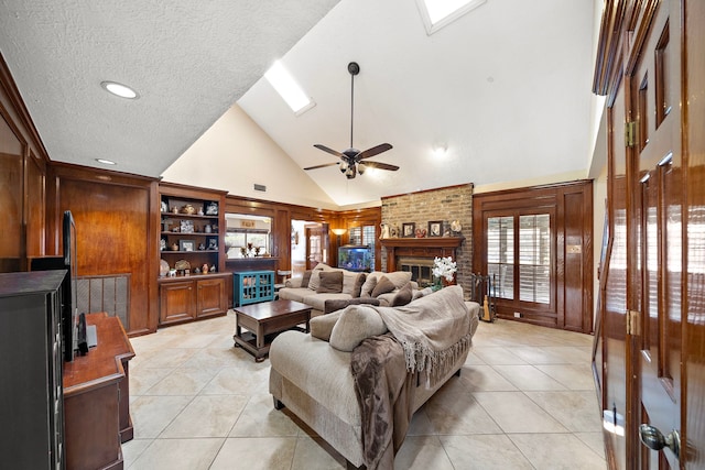 living area featuring light tile patterned floors, a ceiling fan, high vaulted ceiling, a fireplace, and a textured ceiling