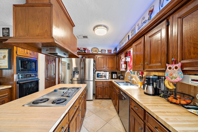 kitchen with visible vents, a sink, black appliances, a textured ceiling, and wood counters