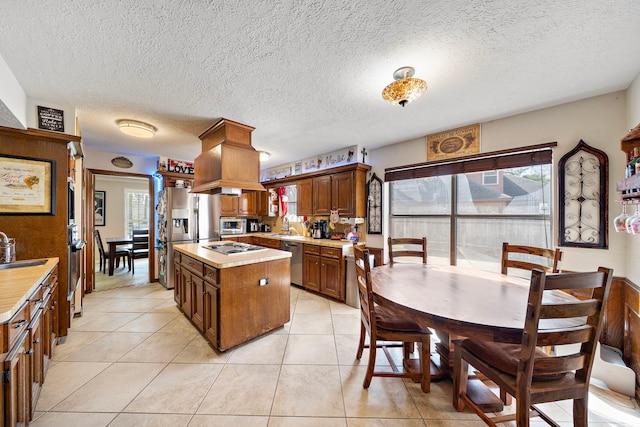 kitchen with a sink, light countertops, light tile patterned flooring, and stainless steel appliances