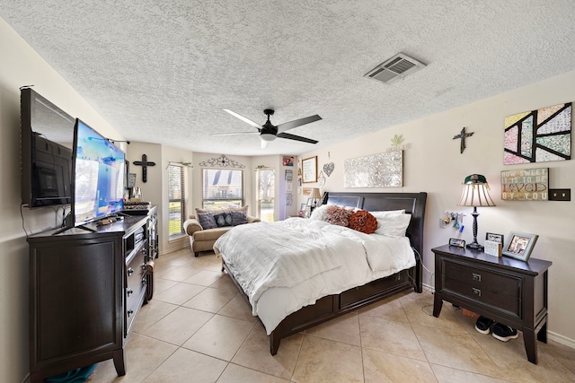 bedroom featuring light tile patterned flooring, visible vents, a textured ceiling, and ceiling fan