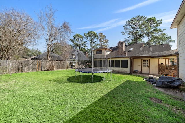 view of yard with a trampoline and fence