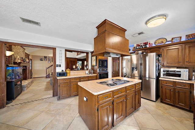 kitchen featuring visible vents, black appliances, a center island, light countertops, and light tile patterned floors