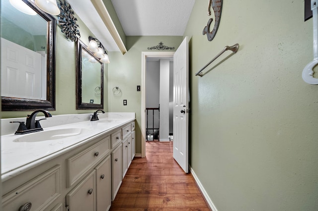 bathroom with a sink, baseboards, wood finished floors, and double vanity