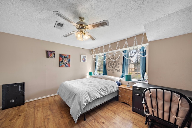 bedroom with ceiling fan, visible vents, a textured ceiling, and light wood-style flooring