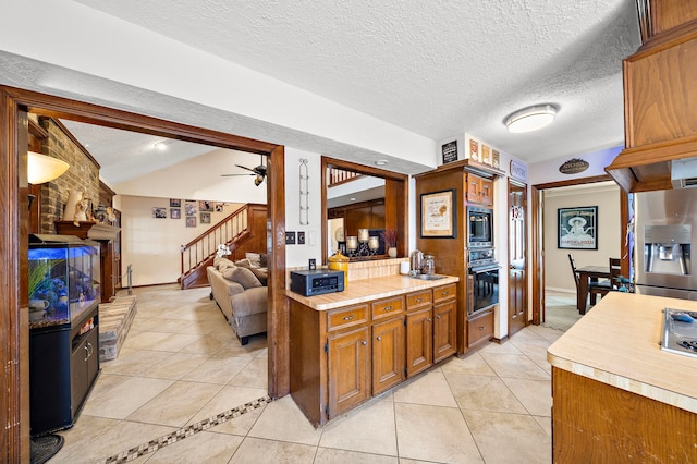 kitchen featuring light countertops, vaulted ceiling, light tile patterned flooring, stainless steel appliances, and a sink