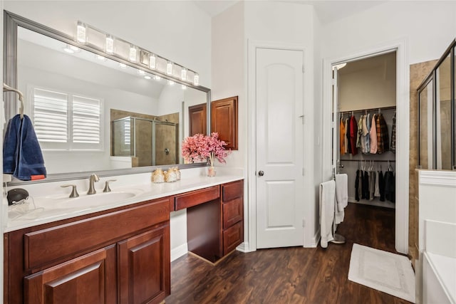 bathroom with a walk in closet, wood finished floors, a stall shower, and vanity