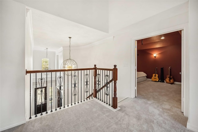 hall featuring a chandelier, baseboards, a high ceiling, and carpet